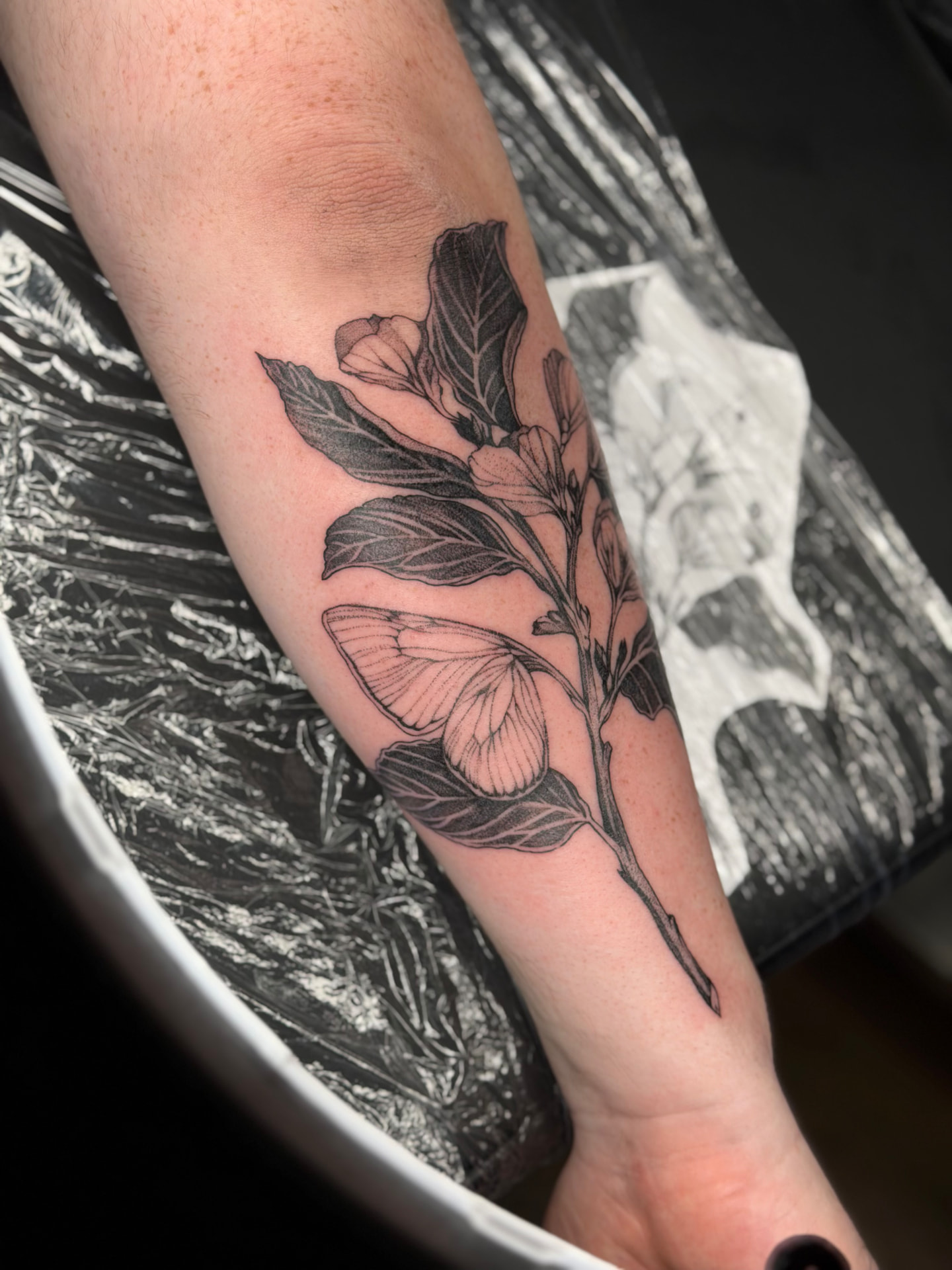 Botanical Tattoo mit blühendem Zweig und Motte am Unterarm